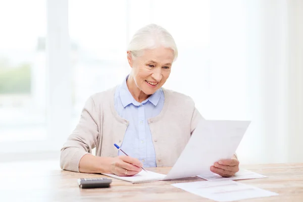 Mulher idosa com papéis e calculadora em casa — Fotografia de Stock