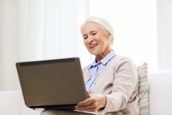 Šťastný starší žena s laptopem doma — Stock fotografie