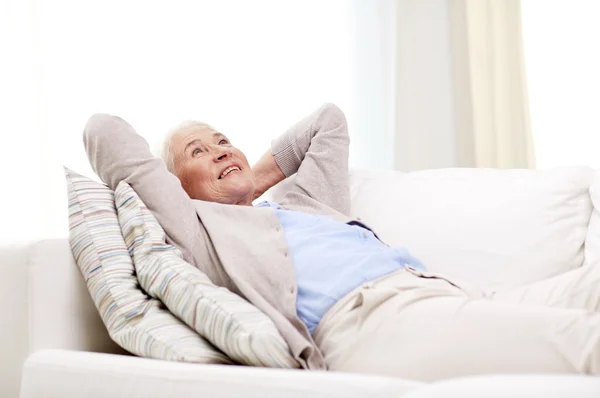 Glückliche Seniorin ruht sich daheim auf Sofa aus — Stockfoto