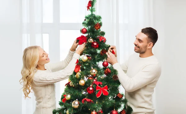 Feliz pareja decorando árbol de Navidad en casa —  Fotos de Stock