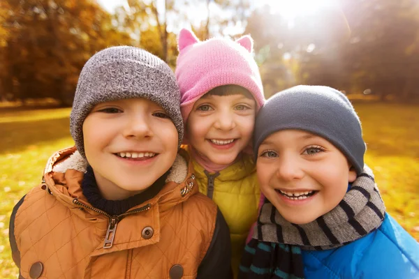 Group of happy children hugging in autumn park — Stock Photo, Image