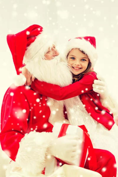Lachende meisje santa claus knuffelen met cadeau thuis — Stockfoto