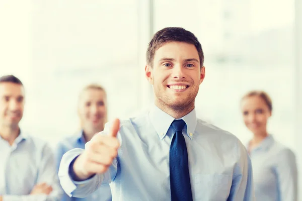 Sonriente hombre de negocios mostrando pulgares hacia arriba en la oficina — Foto de Stock