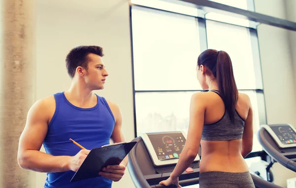 Femme avec entraîneur sur tapis roulant dans la salle de gym — Photo