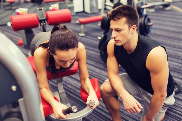 Mujer joven con entrenador haciendo ejercicio en la máquina de gimnasio —  Fotos de Stock