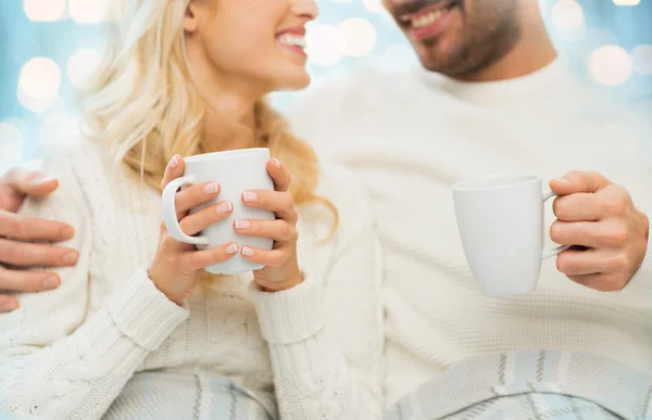 Close up of happy couple with tea cups at home — Stock Photo, Image