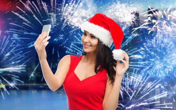 Woman in santa hat taking selfie by smartphone — Stock Photo, Image