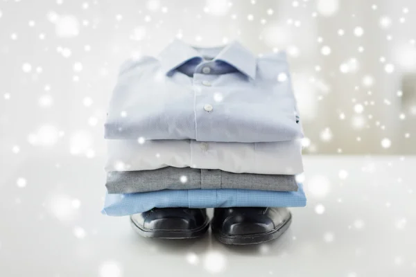 Close up of folded male shirts and shoes on table — Stock Photo, Image