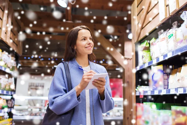 Mujer feliz con bloc de notas en el mercado — Foto de Stock