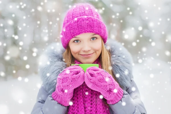 Uśmiechnięta młoda kobieta z kubkiem w zimowym lesie — Zdjęcie stockowe