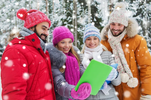 Lachende vrienden met tablet pc in winter forest — Stockfoto