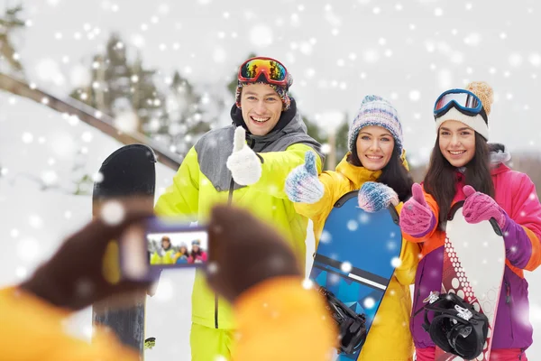 Amigos felices con tablas de snowboard y smartphone —  Fotos de Stock