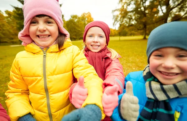 Happy children showing thumbs up in autumn park — ストック写真