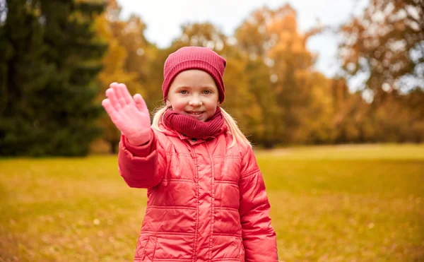 Szczęśliwa dziewczynka macha ręką w jesienny park — Zdjęcie stockowe