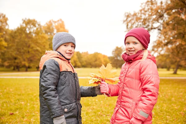 Petit garçon donnant feuilles d'érable d'automne à la fille — Photo