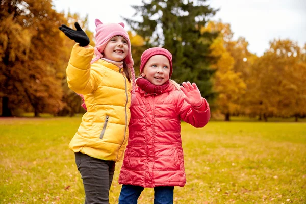 Zwei glückliche kleine Mädchen winken im Herbstpark — Stockfoto