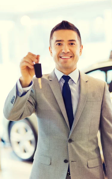 Glücklicher Mann zeigt Schlüssel auf Automesse oder Autosalon — Stockfoto