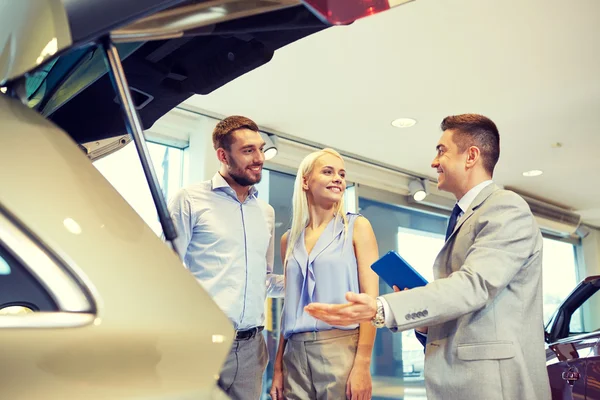 Happy couple with car dealer in auto show or salon — Stock Photo, Image