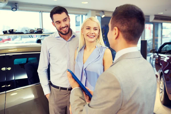 Happy couple with car dealer in auto show or salon — Stock Photo, Image