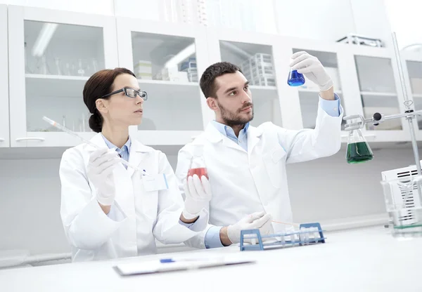 Jovens cientistas que fazem testes ou pesquisas em laboratório — Fotografia de Stock