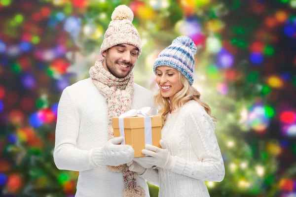 Smiling couple in winter clothes with gift box — Stock Photo, Image