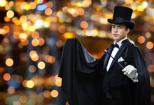 Magician in top hat showing trick with magic wand — Stock fotografie