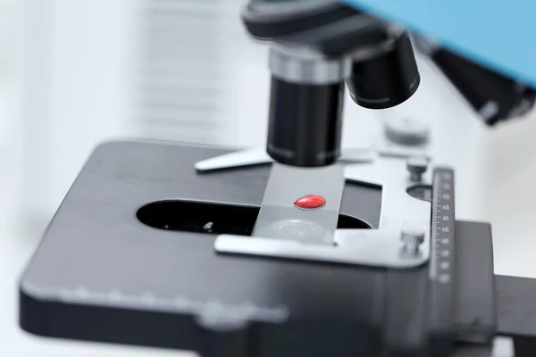 Zblízka mikroskopu a krevního vzorku v laboratoři — Stock fotografie
