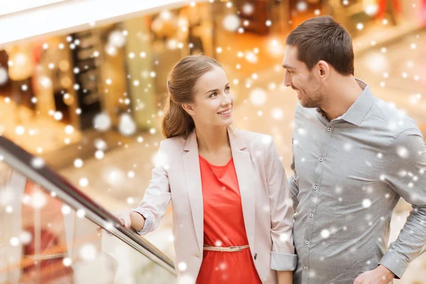 Pareja con bolsas de compras en escalera mecánica en el centro comercial —  Fotos de Stock