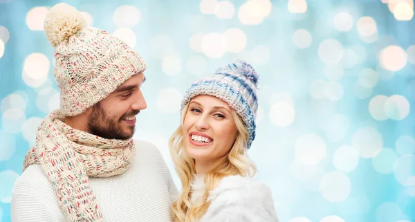 Smiling couple in winter clothes over blue lights — 图库照片