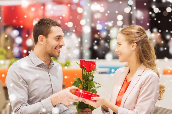 Feliz pareja con regalo y flores en el centro comercial —  Fotos de Stock