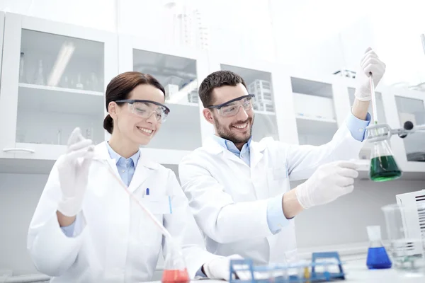 Jóvenes científicos haciendo pruebas o investigaciones en laboratorio — Foto de Stock