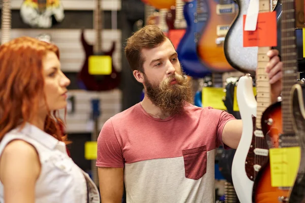 Couple of musicians with guitar at music store — Stock Photo, Image