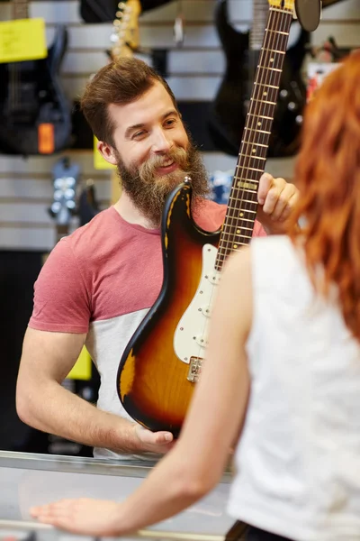 Assistentin zeigt Kundengitarre im Musikladen — Stockfoto