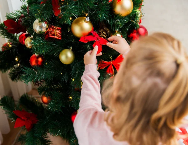 Nahaufnahme eines Kindes, das den Weihnachtsbaum schmückt Stockfoto