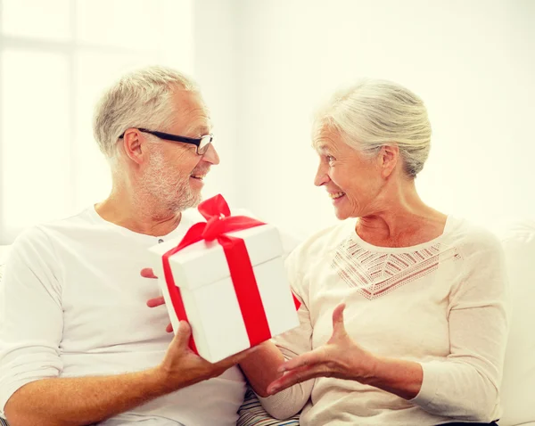 Feliz pareja de ancianos con caja de regalo en casa —  Fotos de Stock