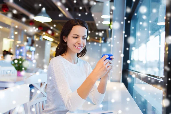 Улыбающаяся женщина со смартфоном в кафе — стоковое фото