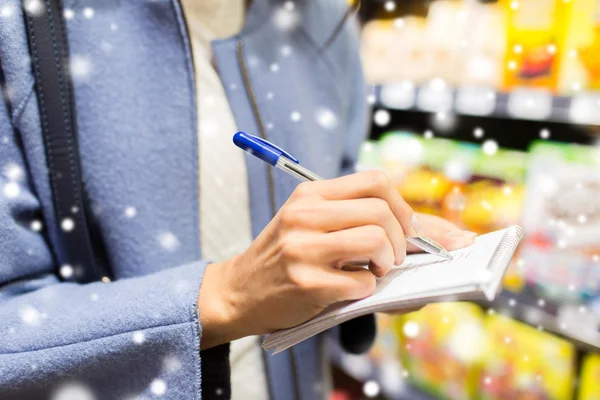 Close up of woman writing to notepad in grocery — Stockfoto