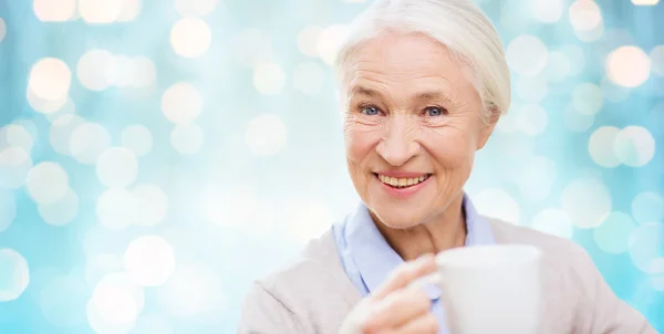Счастливая пожилая женщина с чашкой чая или кофе — стоковое фото