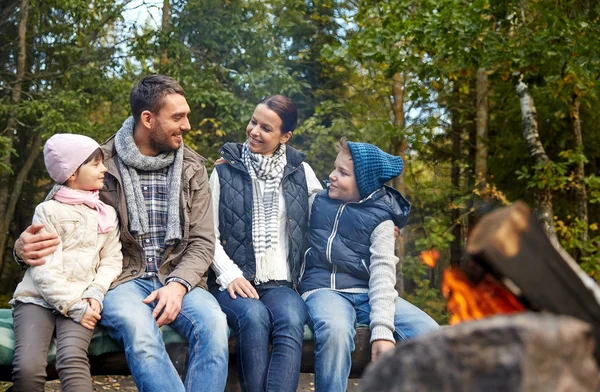 Família feliz sentado no banco no acampamento fogo — Fotografia de Stock