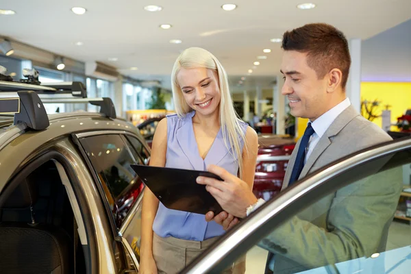 Donna felice con rivenditore di auto in salone o salone di auto — Foto Stock