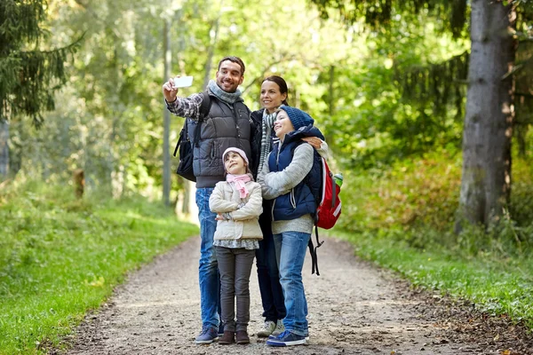 family taking selfie with smartphone in woods