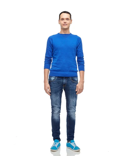 Улыбающийся молодой человек в синем свитере и джинсах — стоковое фото