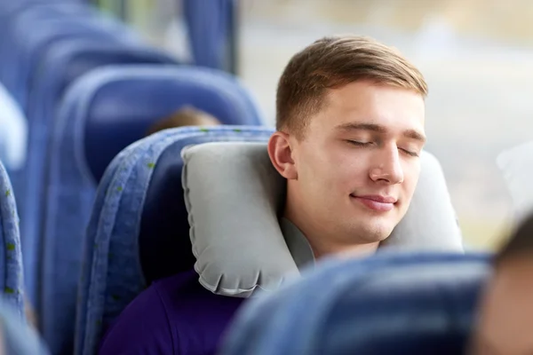Happy young man sleeping in travel bus with pillow — Stock Photo, Image