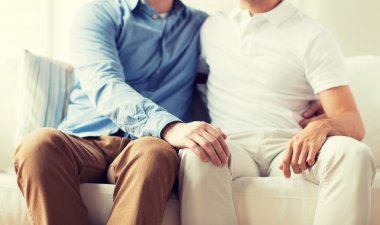 close up of happy male gay couple hugging at home clipart