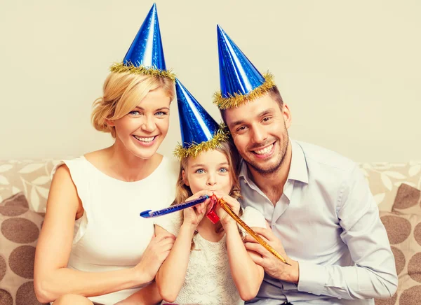 Smiling family in blue hats blowing favor horns — Stock Photo, Image