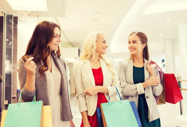 Gelukkig jonge vrouwen met boodschappentassen in winkelcentrum — Stockfoto