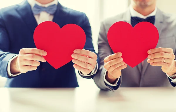 Close up of male gay couple holding red hearts — Stock Photo, Image