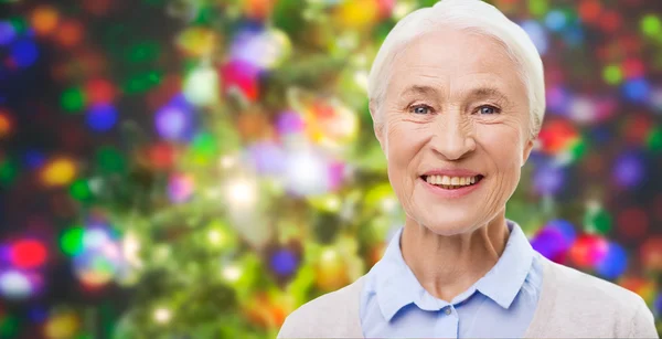 Happy senior woman face over christmas lights — Stock Fotó