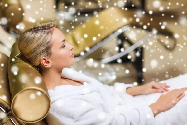 Beautiful young woman sitting in bath robe at spa — Stock Photo, Image