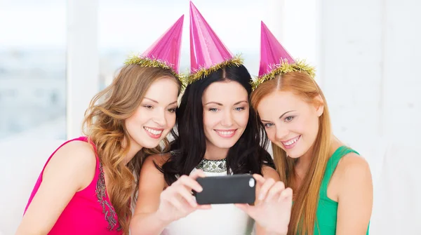 Tre leende kvinnor i hatt har kul med kameran — Stockfoto